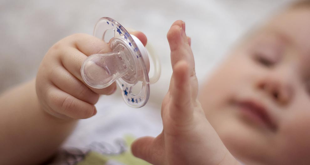 A baby's hand holds a pacifier.