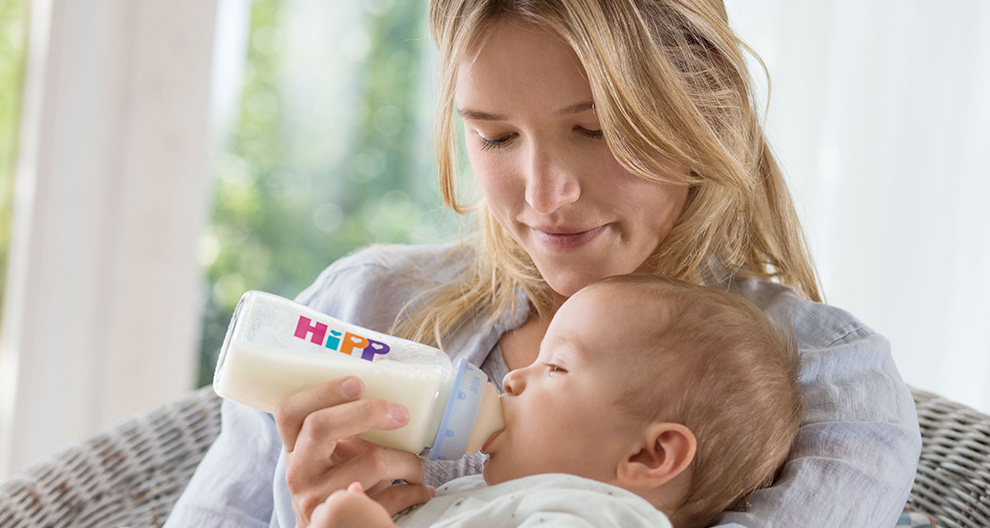 A woman feeds a baby with a Hipp bottle.